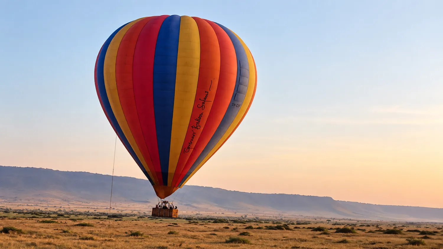 A balloon lifting off over the Masai Mara at first light